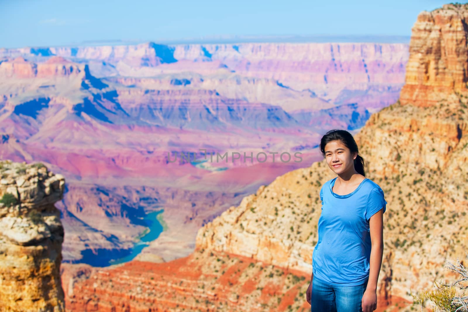 Young teen girl standing at the Grand Canyon, Arizona, in front of colorful canyon walls 