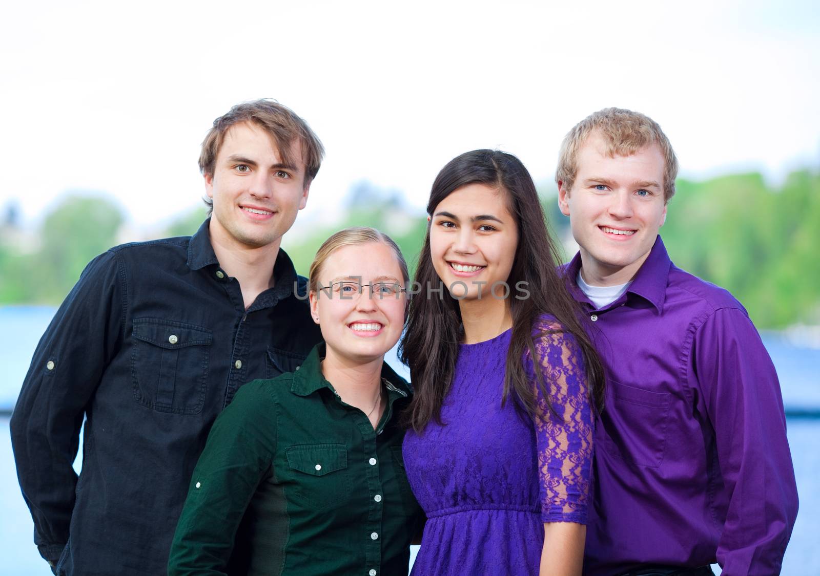 Four young multiethnic friends in early twenties  standing together outdoors