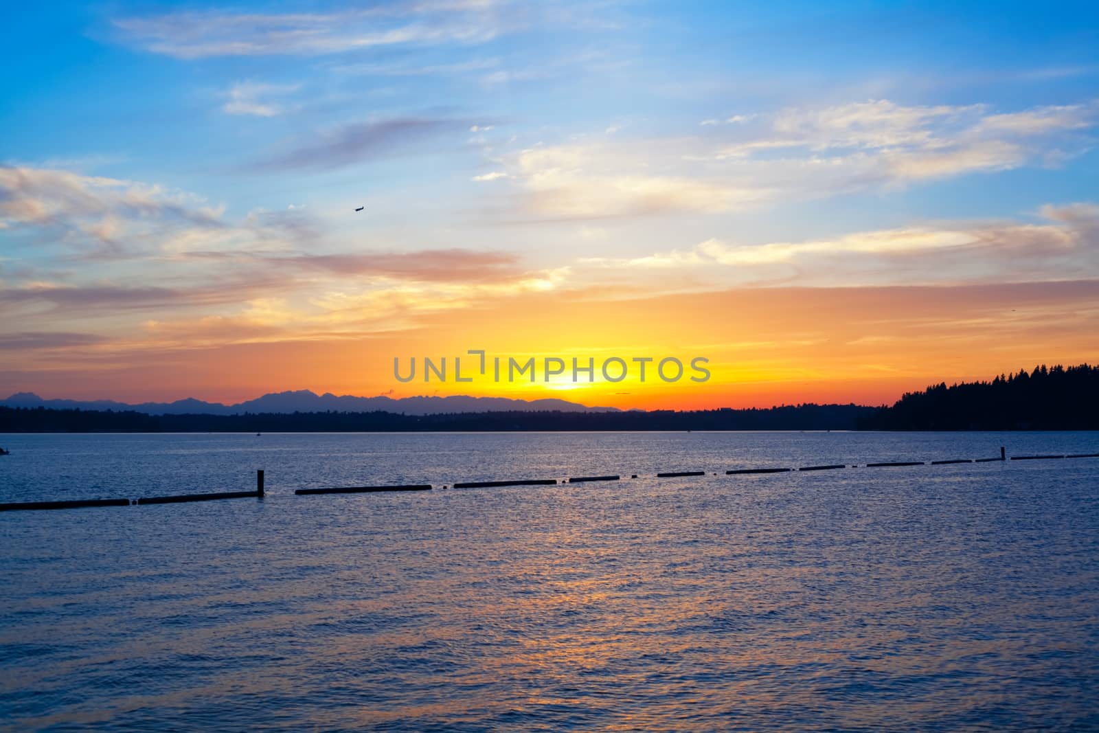 Beautiful yellow orange sunset with azure sky over blue waters of lake