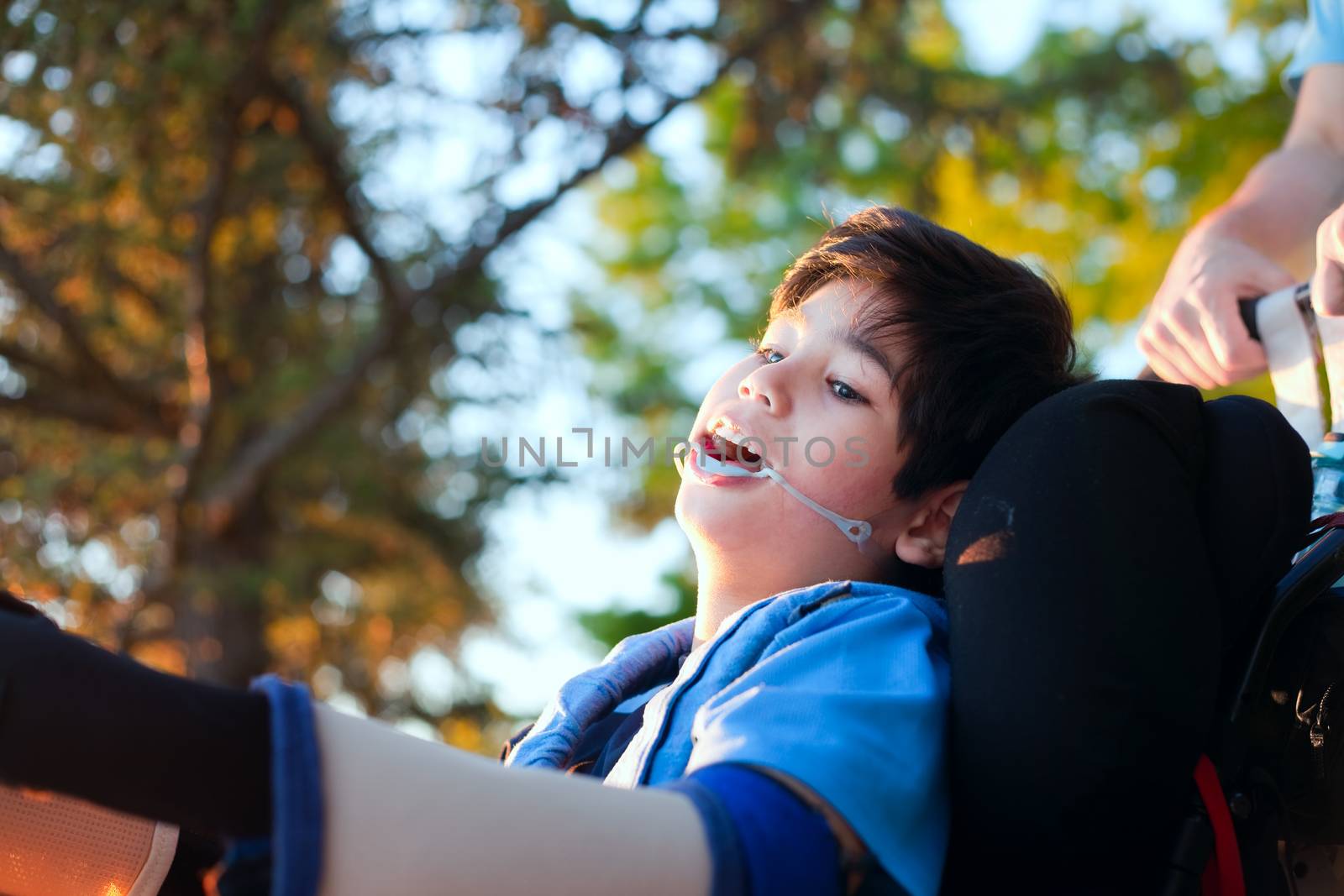 Handsome biracial disabled boy in wheelchair, enjoying sunset at park outdoors