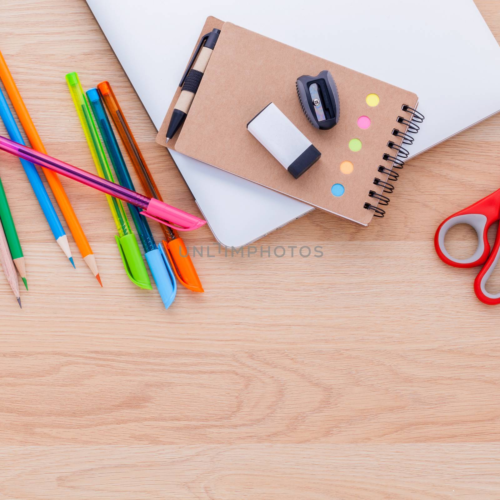 Back to school concept with school supplies laptop ,notebook, pen and colored pencil on wooden table .