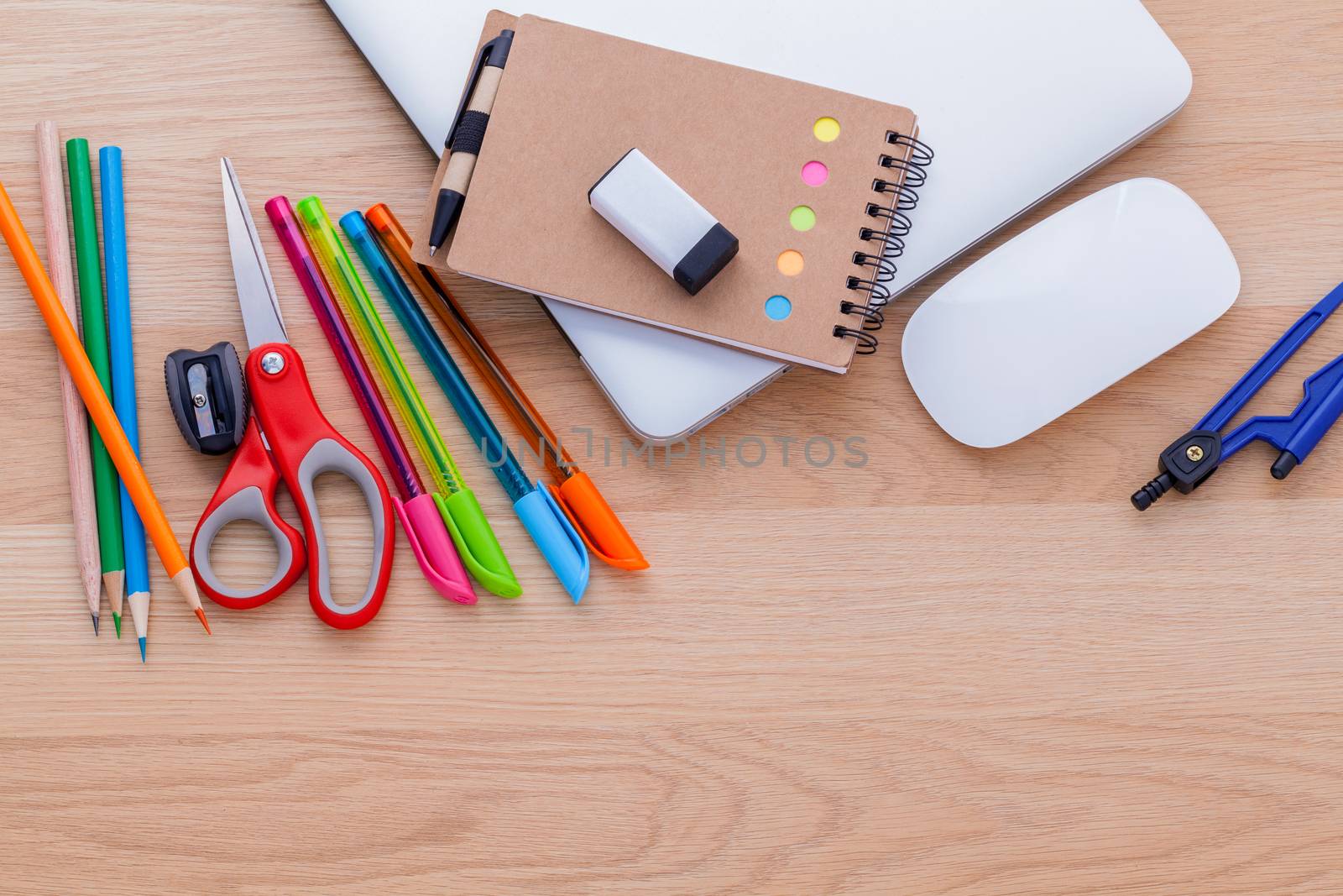 Back to school concept with school supplies laptop ,book, pen,mouse,and colored pencil on wooden table .