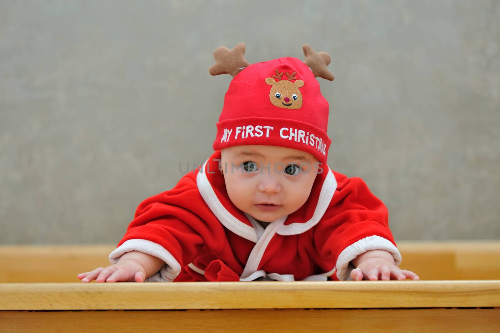 A baby in a Santa suit on stairs