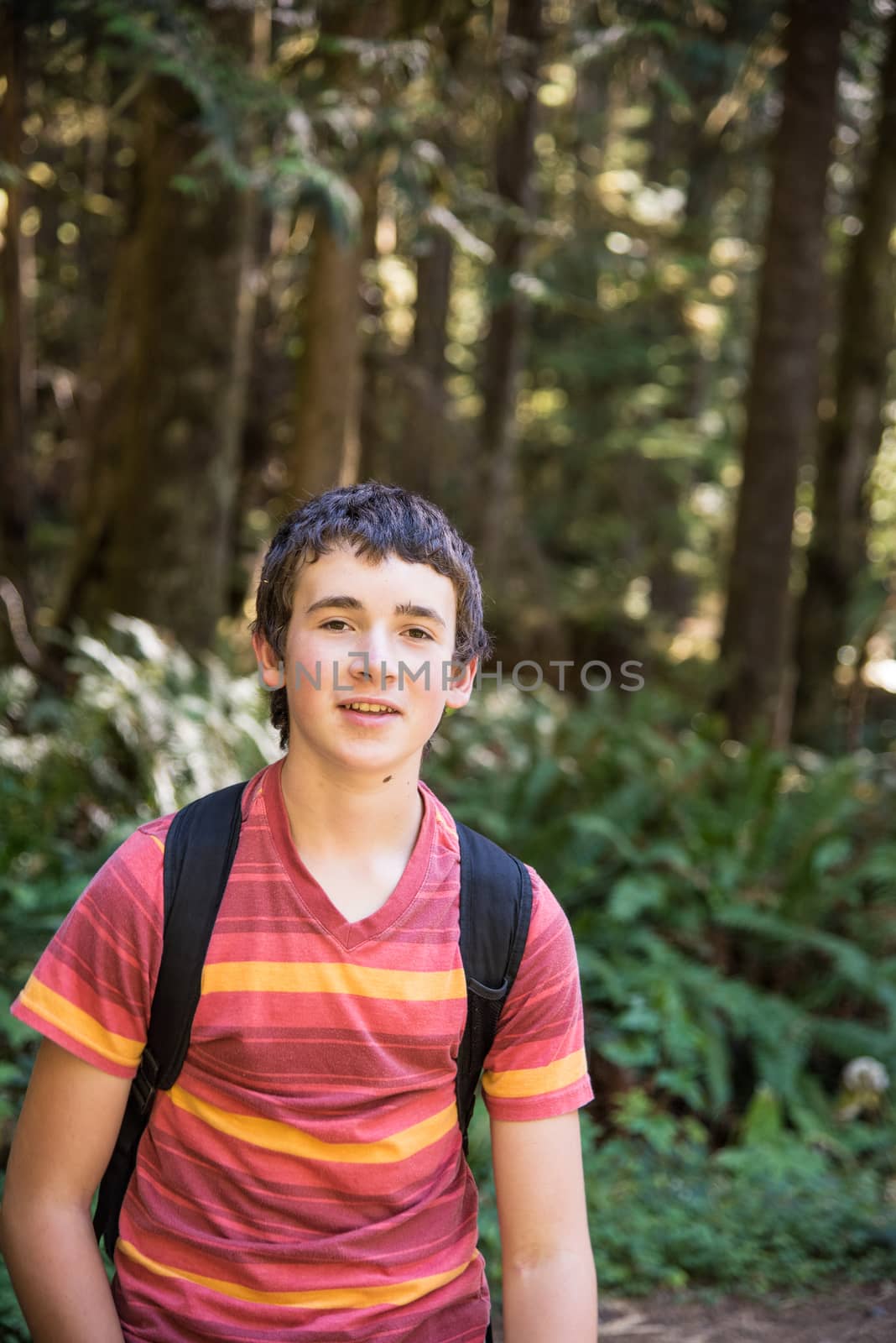 13 year old boy with backpack hiking in forest