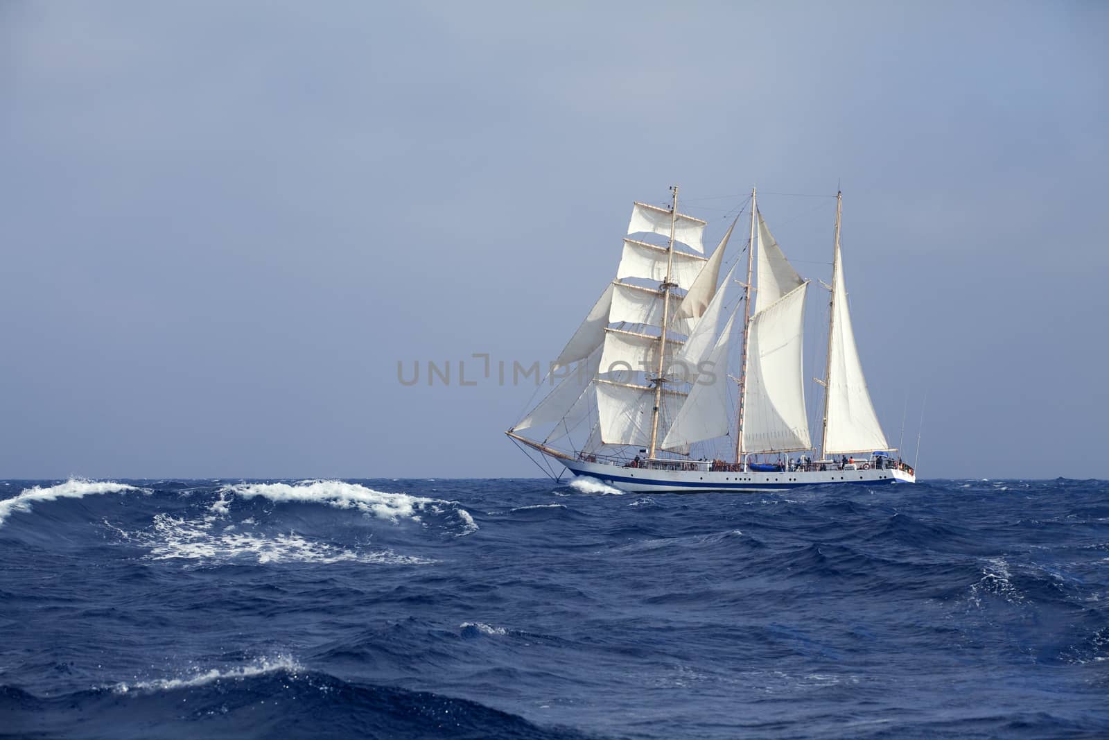 Barquentine with white sails in the calm sea