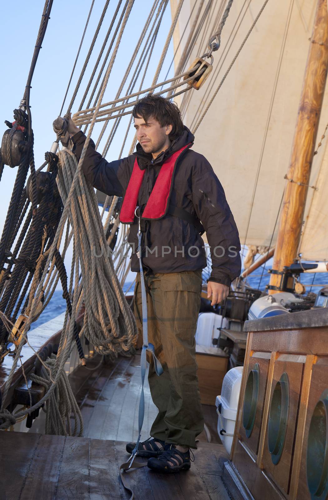 Young sailor onboard with sails behind him