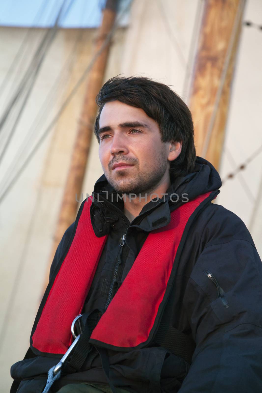 Young sailor on board with sails behind him