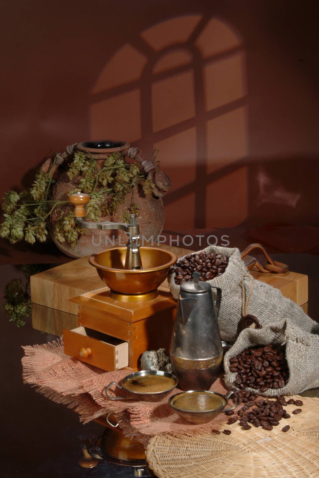 Coffee beans, mill, and ceramic pot ona studio background