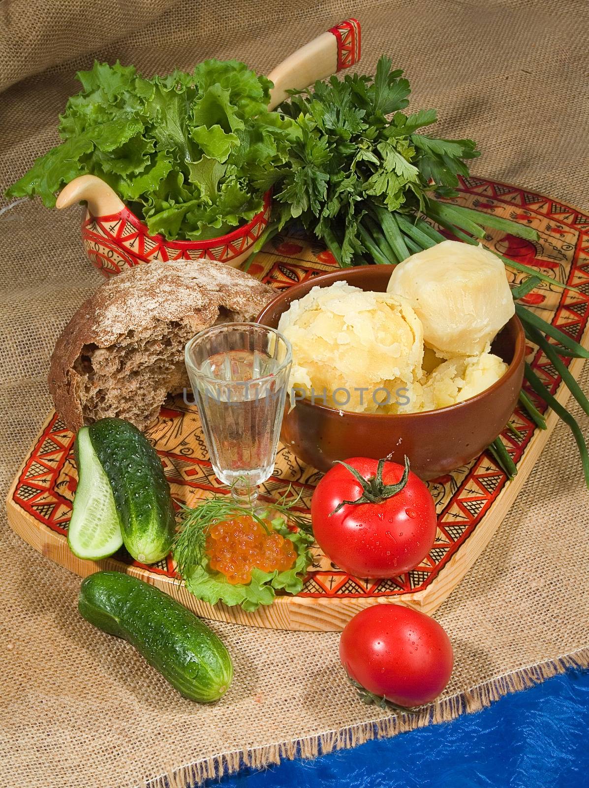 Glass of Russian vodka, tomatoes, greenery, bread and potatoes on canvas