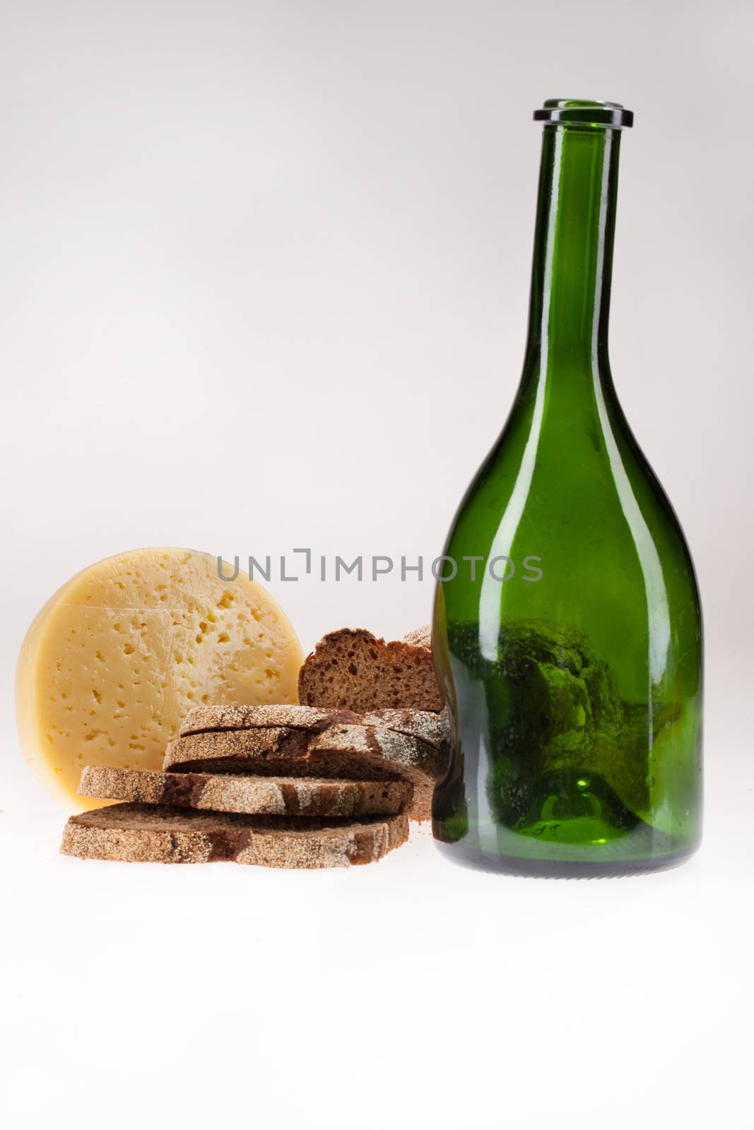 Cheese, pieces of bread and green bottle on isolated background