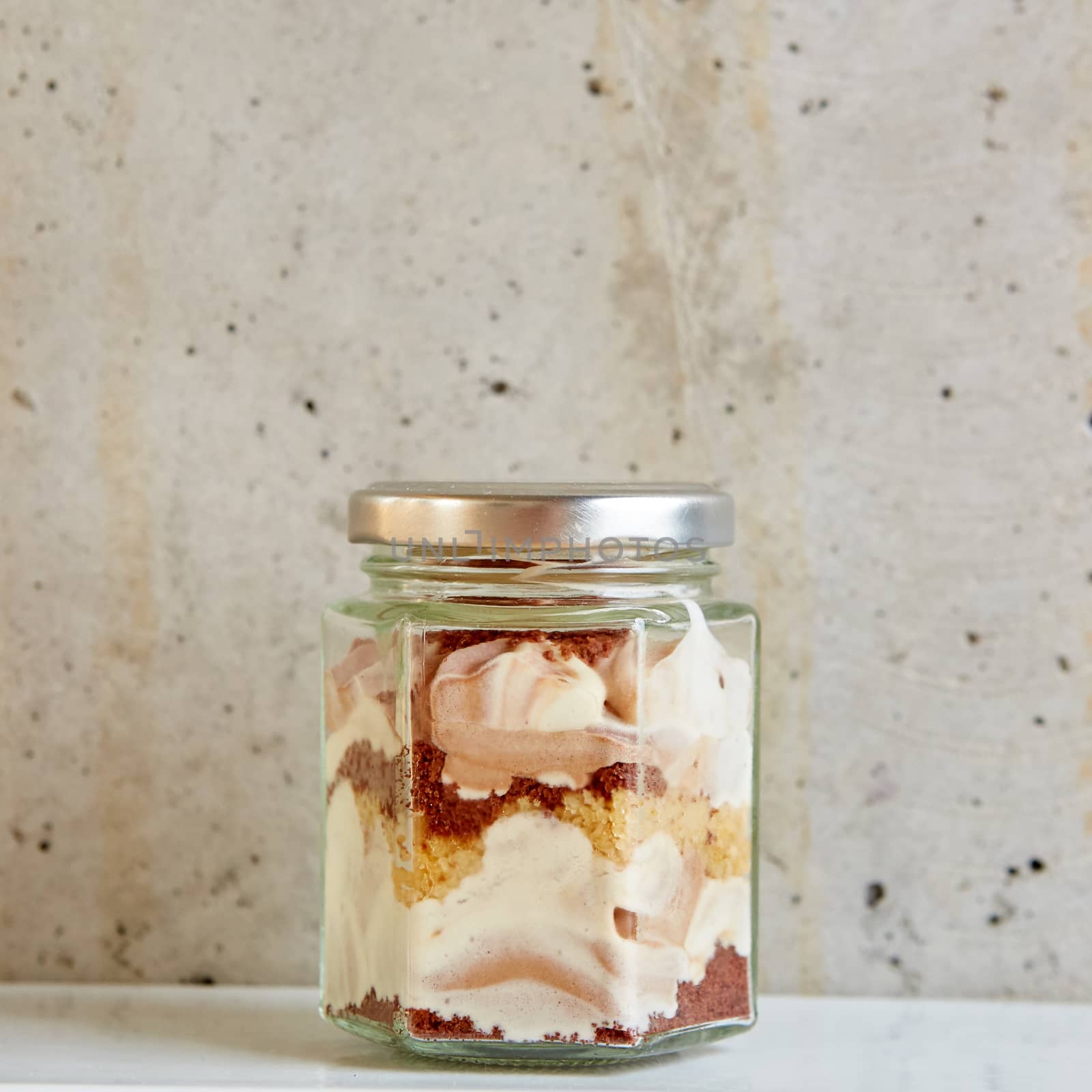 Homemade cheesecake in a glass jar on gray background