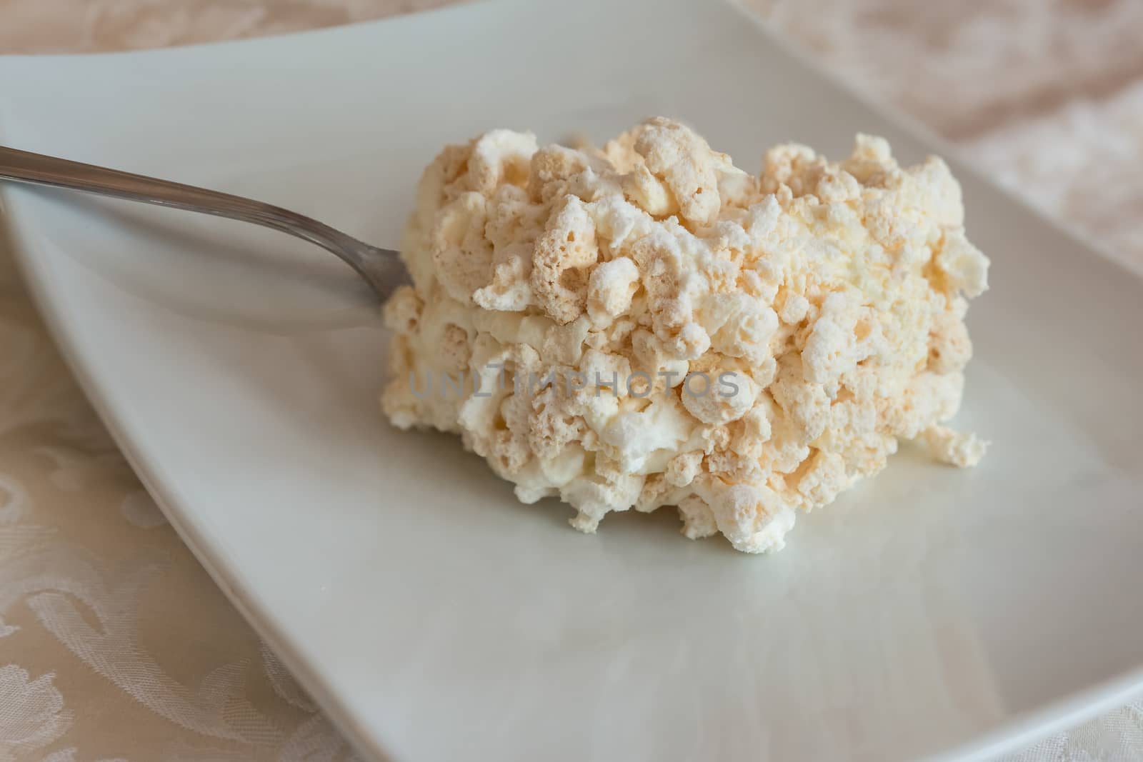 Italian Meringue cake slice with cream and nuts on white plate.