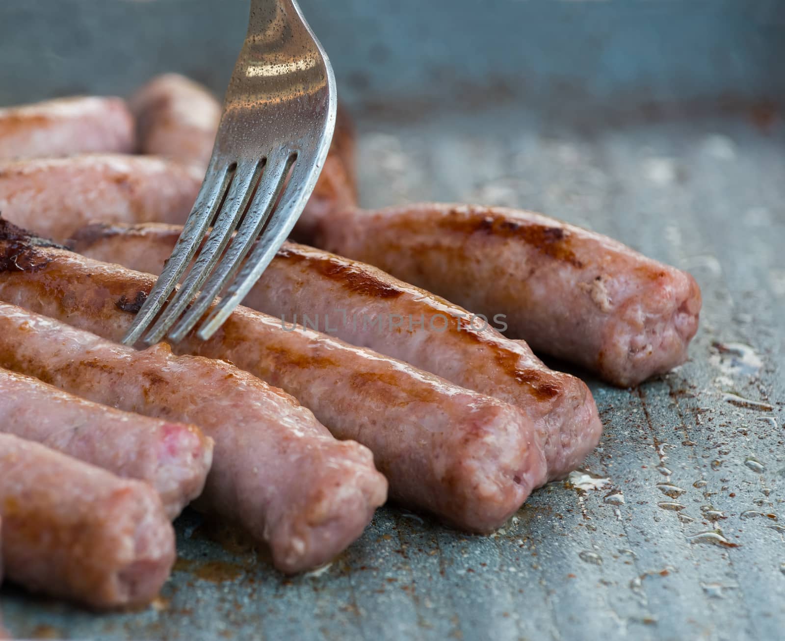 In the picture of the pork sausages they are cooked on the grill with a fork while cooking is controlled.