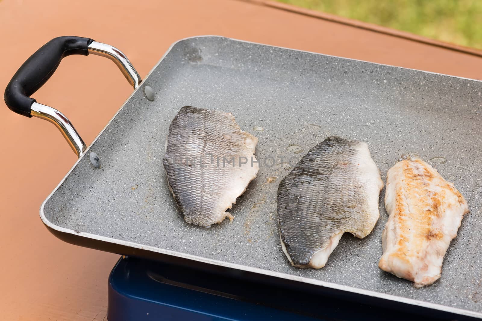 Pictured three fillets of sea bream cooked on the grill outdoor.