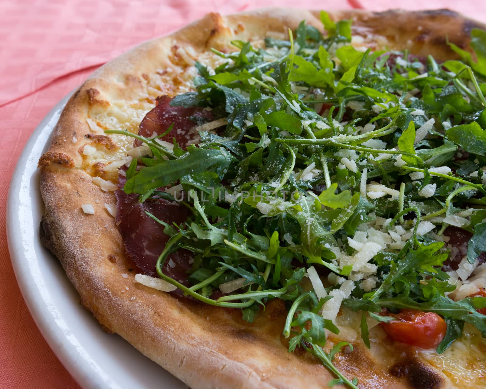 In the picture Italian pizza  with Arcula,cherry tomato,tomato,cheese,mozzarella,parmesan and Bresaola.