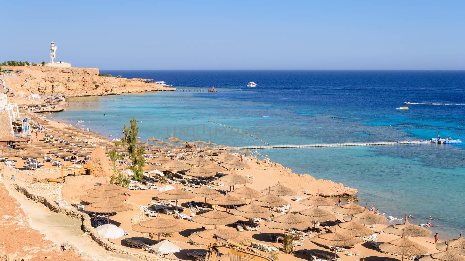 In the picture a typical Egyptian beach in the Red Sea with wood and straw umbrellas and turquoise sea.