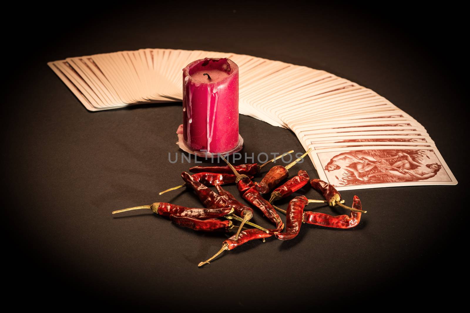 In the pictured a deck of cards open fan , a red candle and red pepper dry.