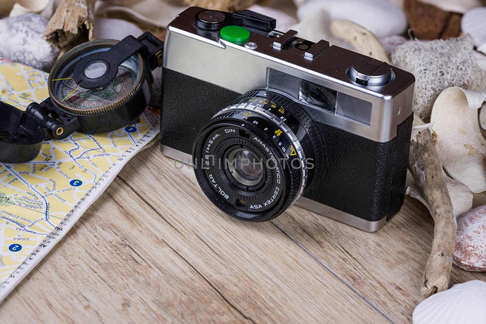 In the picture an analog camera film , a compass and a map, on the sides shells and decorative stones .