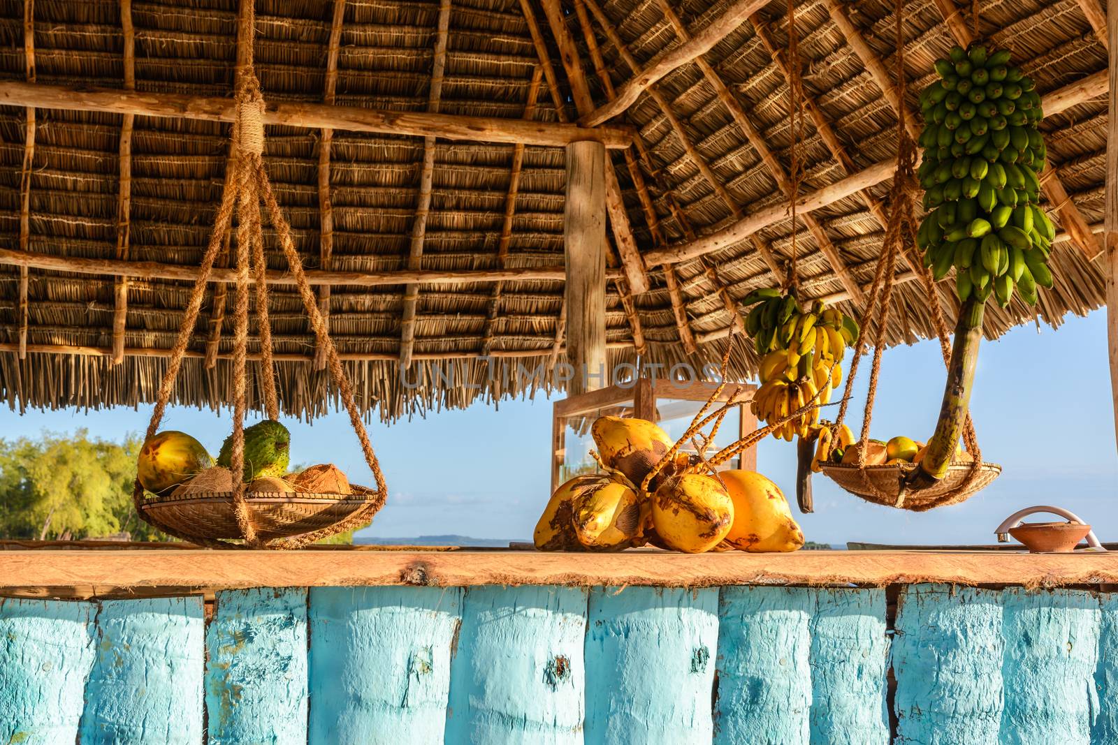 In the picture beach bar in Nungwi ( Zanzibar ) at sunset , with exposed coconut , banana and tropical fruit .This bar is made with cane bamboo,wooden and straw rope.