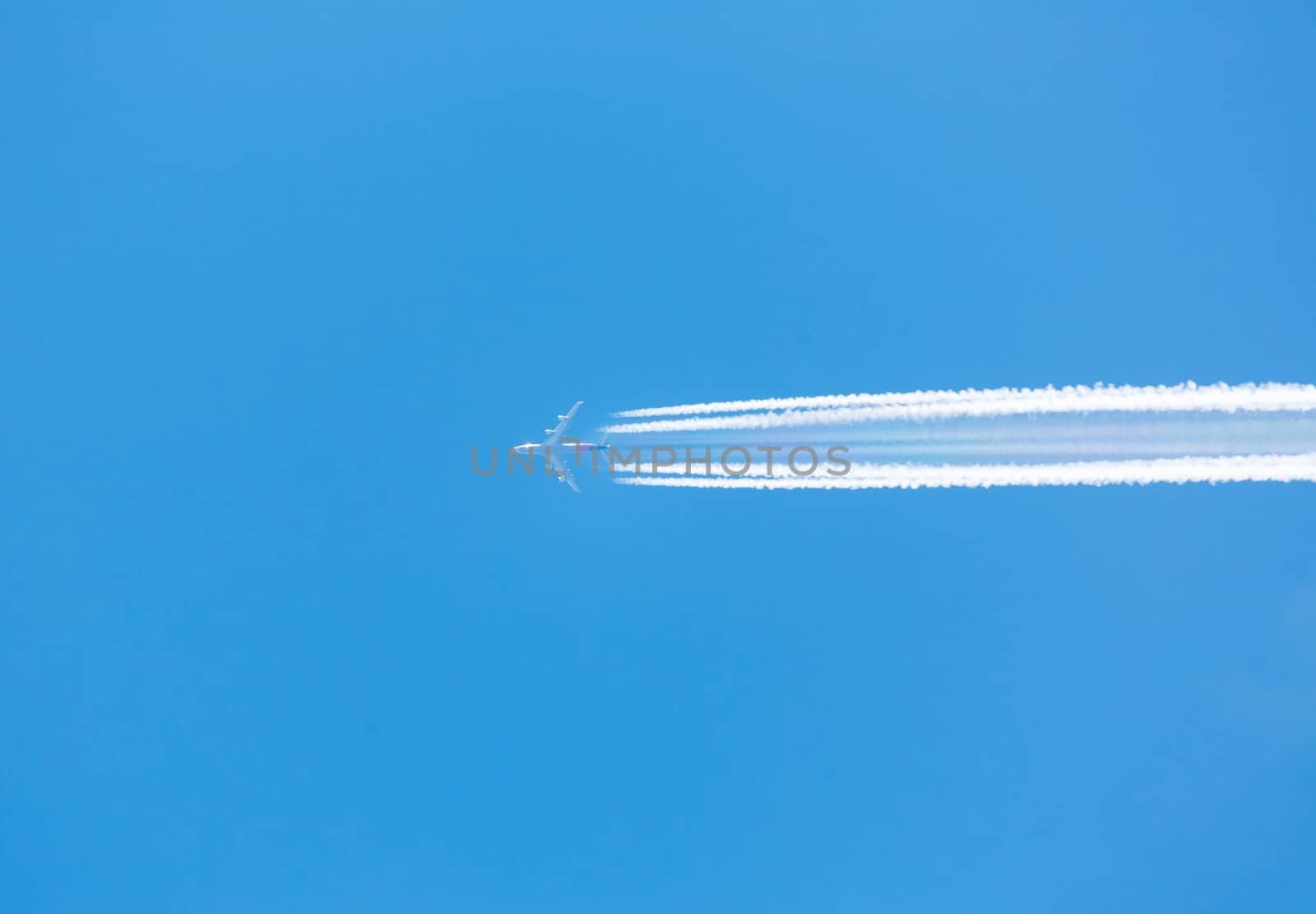 A plane flying on a clear blue sky with vapor trail