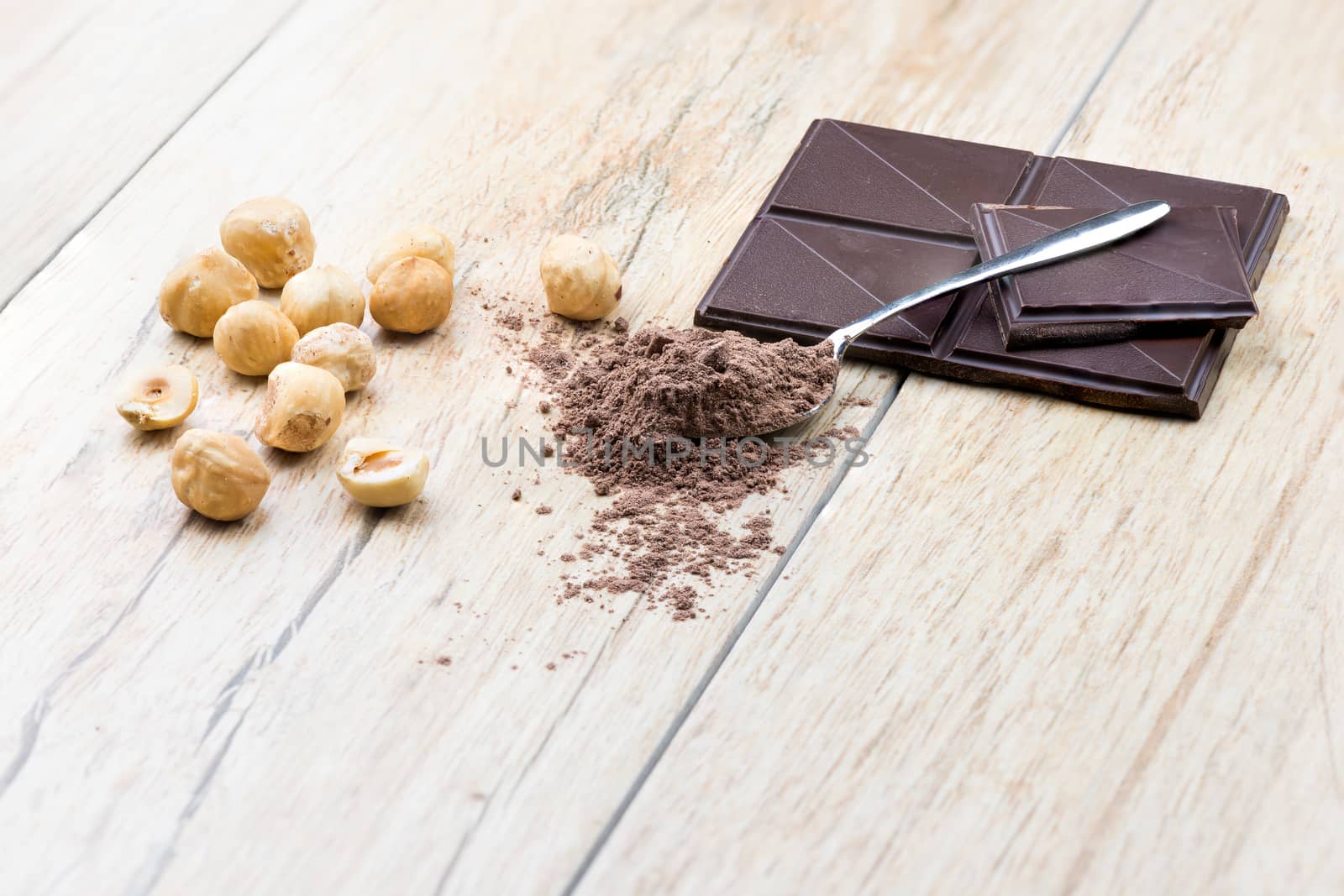 A side  view of chocolate, hazelnuts clean and covered teaspoon cocoa.