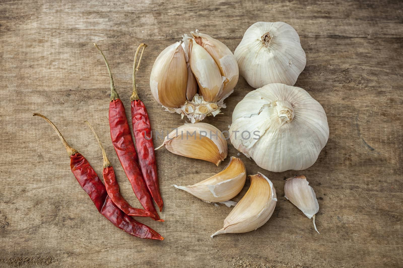 Dried red chili pepper and fresh garlic on wooden background .