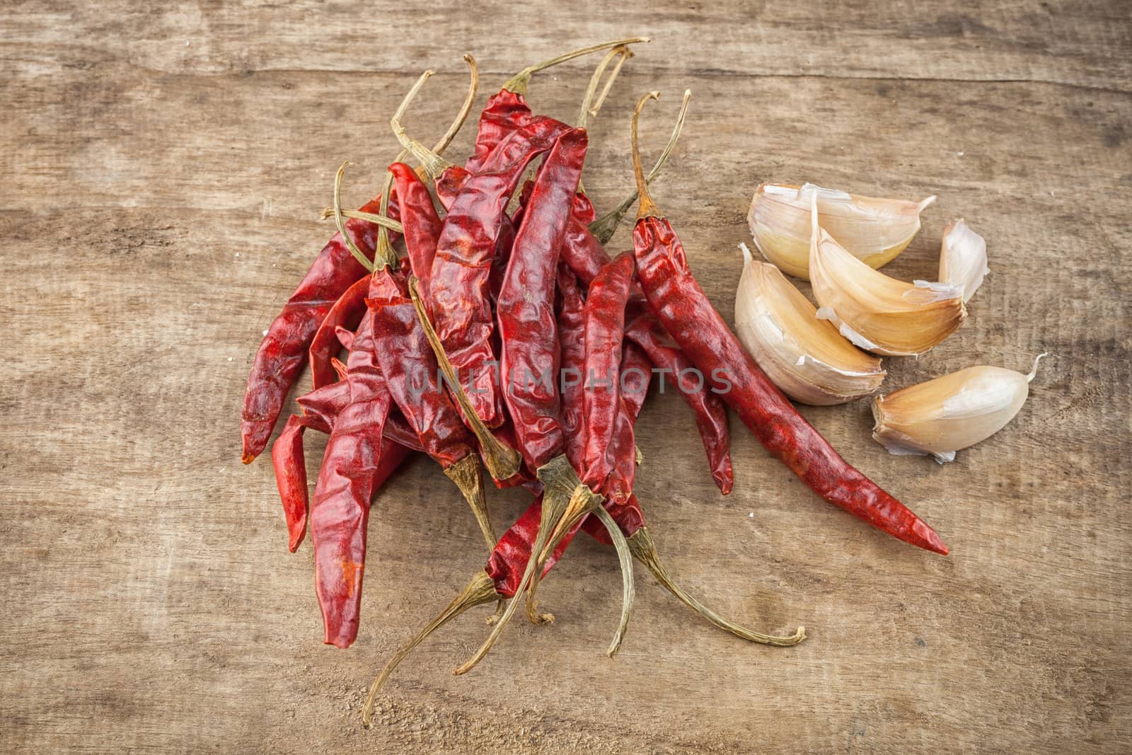 Dried red chili pepper and fresh garlic on wooden background .