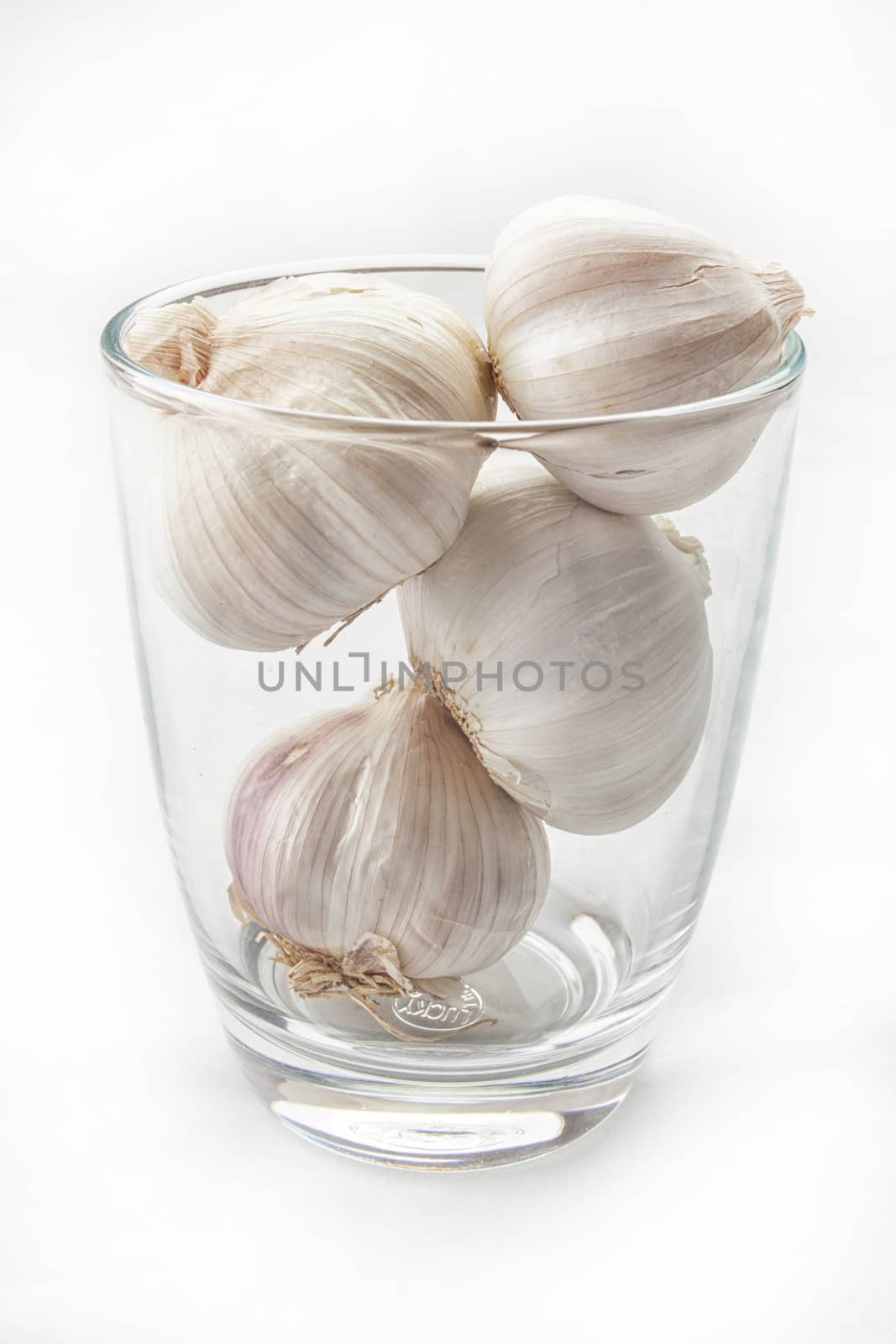 Fresh garlic in glass isolated on white background .