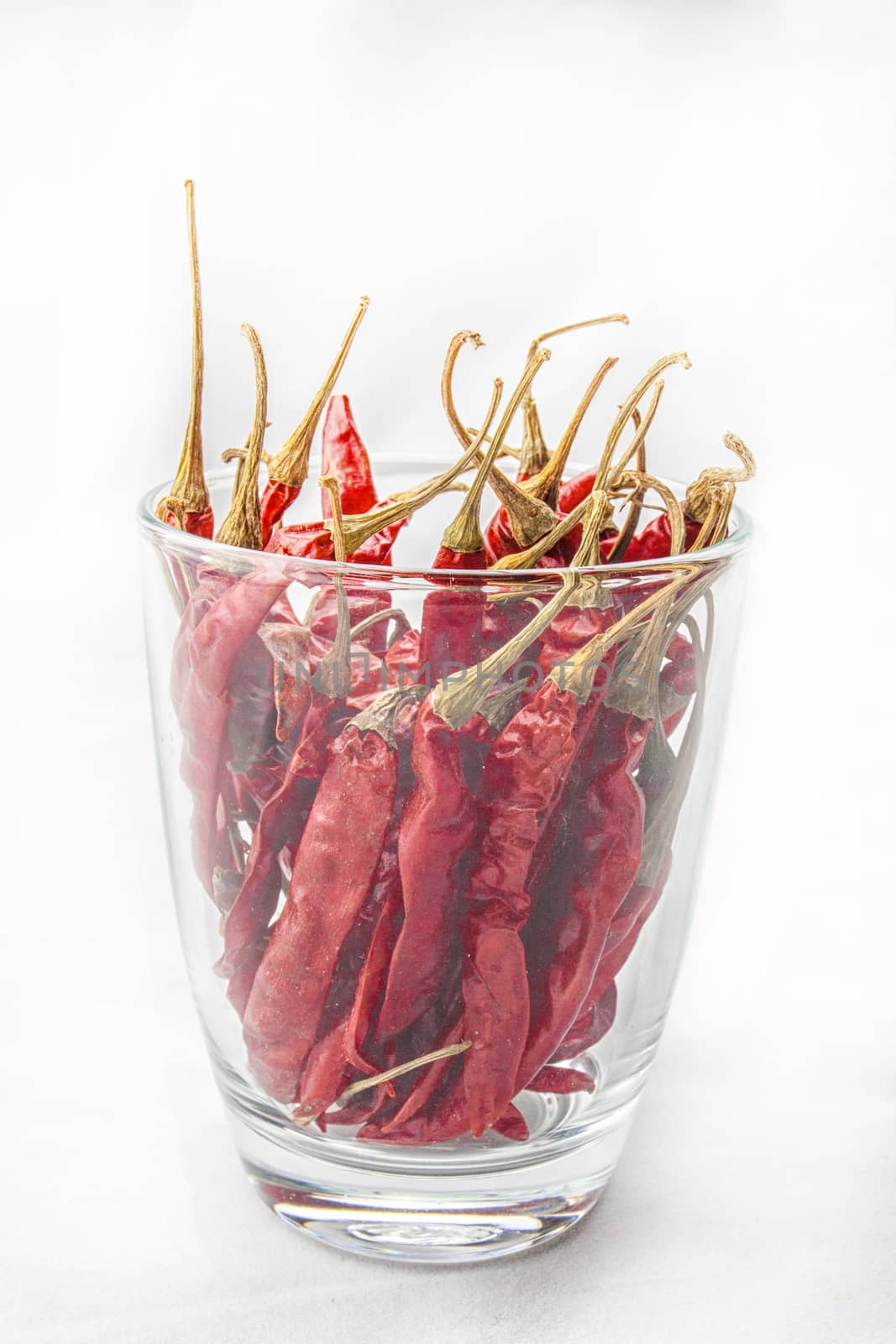 Dried red chili pepper in glass isolated on white background .