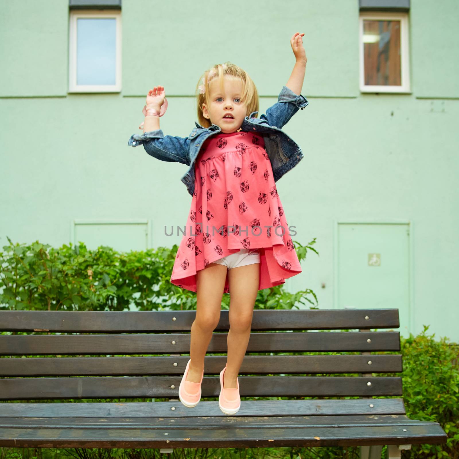 Happy little child, blonde toddler girl jumping on summer day