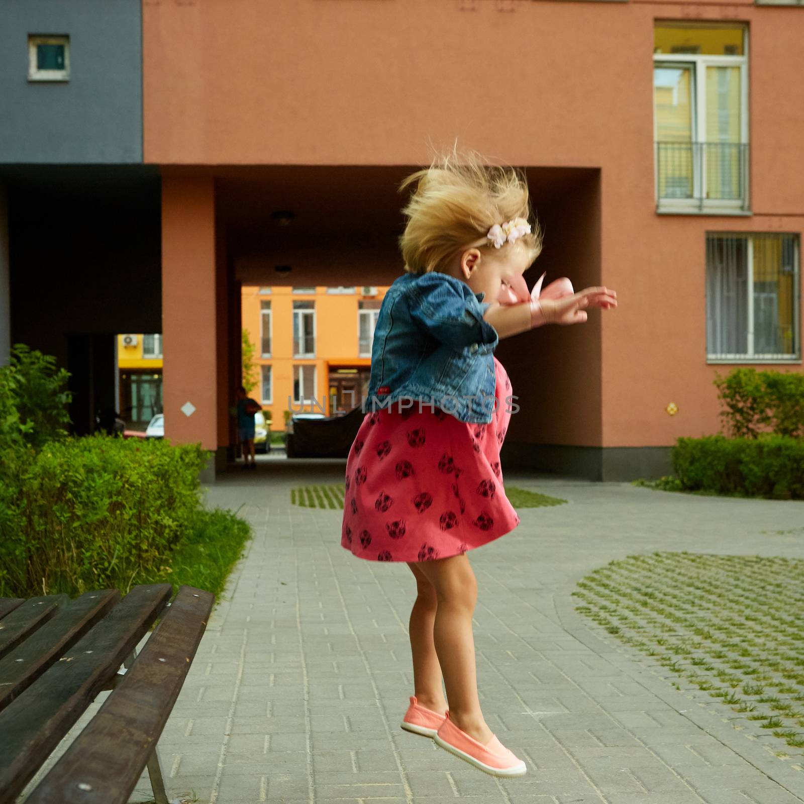 Happy little child, blonde toddler girl jumping on summer day