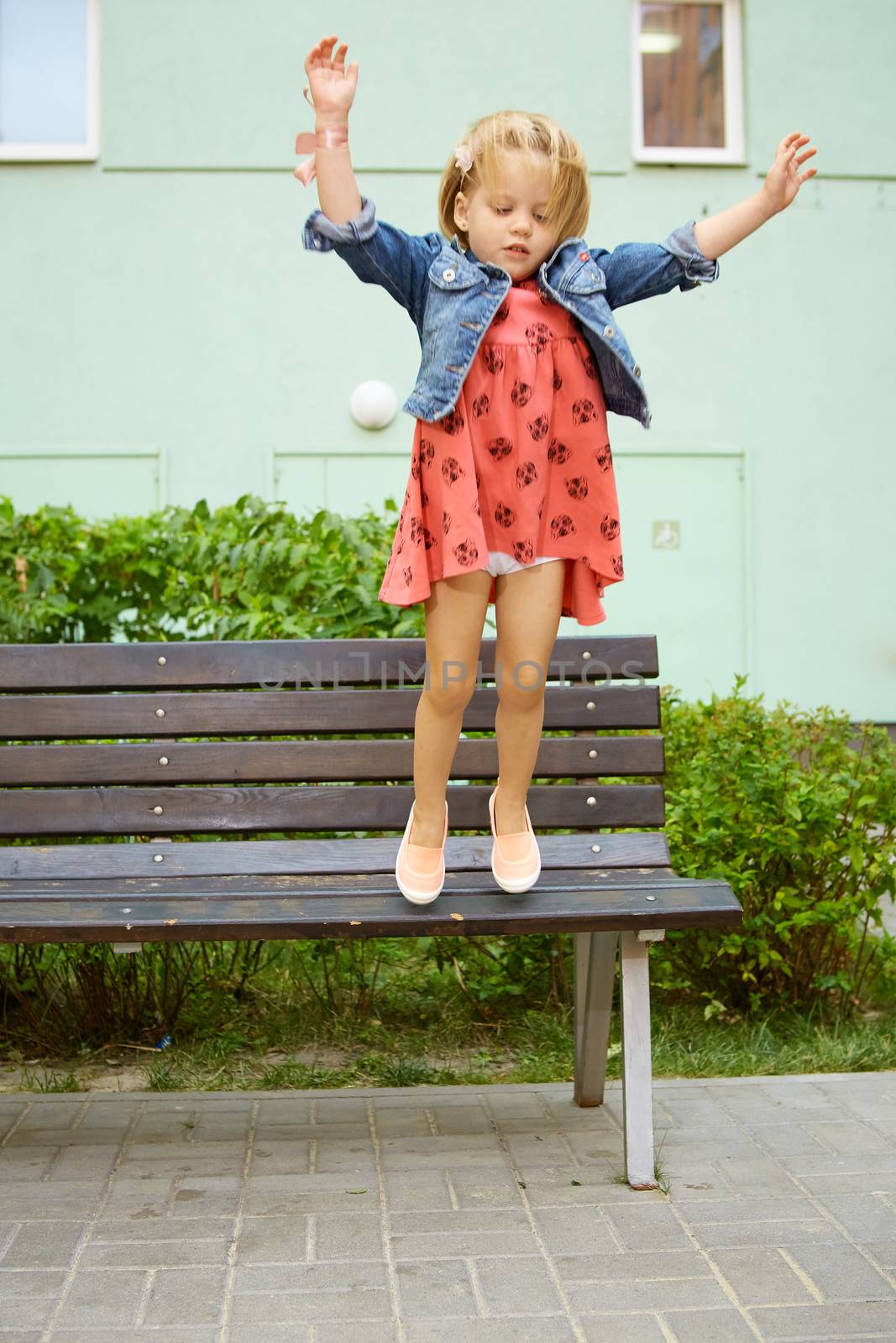Happy little child, blonde toddler girl jumping on summer day