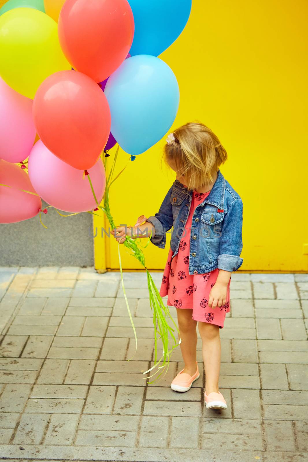 inspiration, happy little girl outdoors with balloons on a yellow background