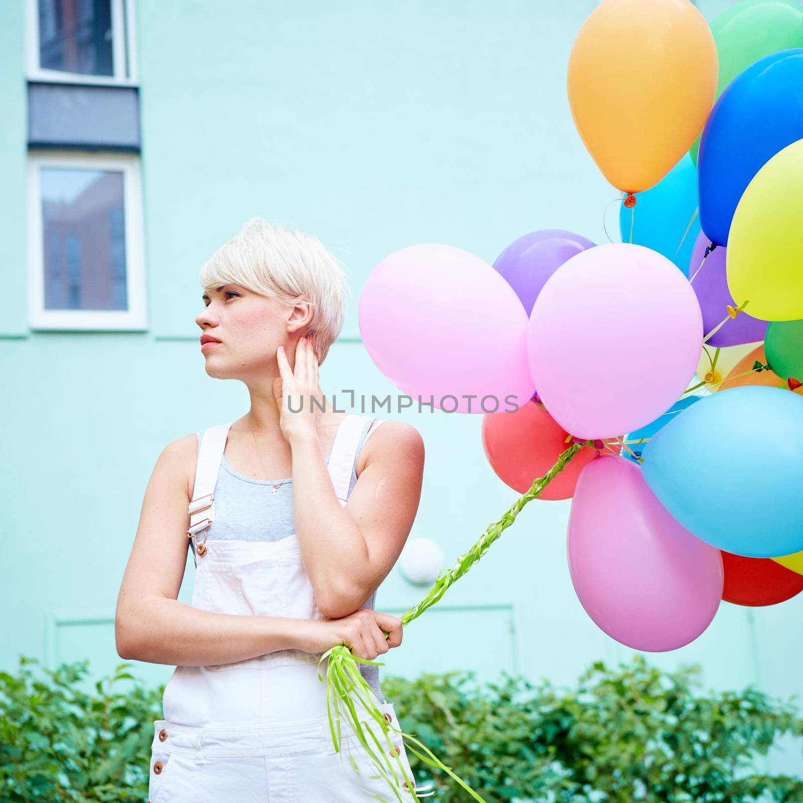 Happy young woman with colorful latex balloons, outdoor