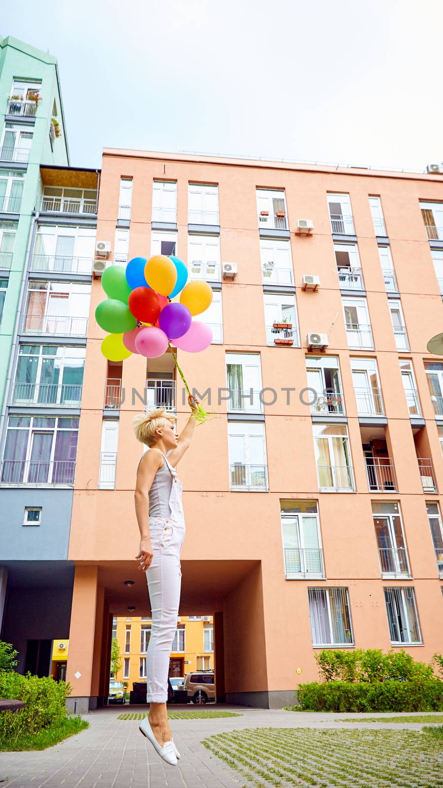 Happy young woman with colorful latex balloons, outdoor, jumping