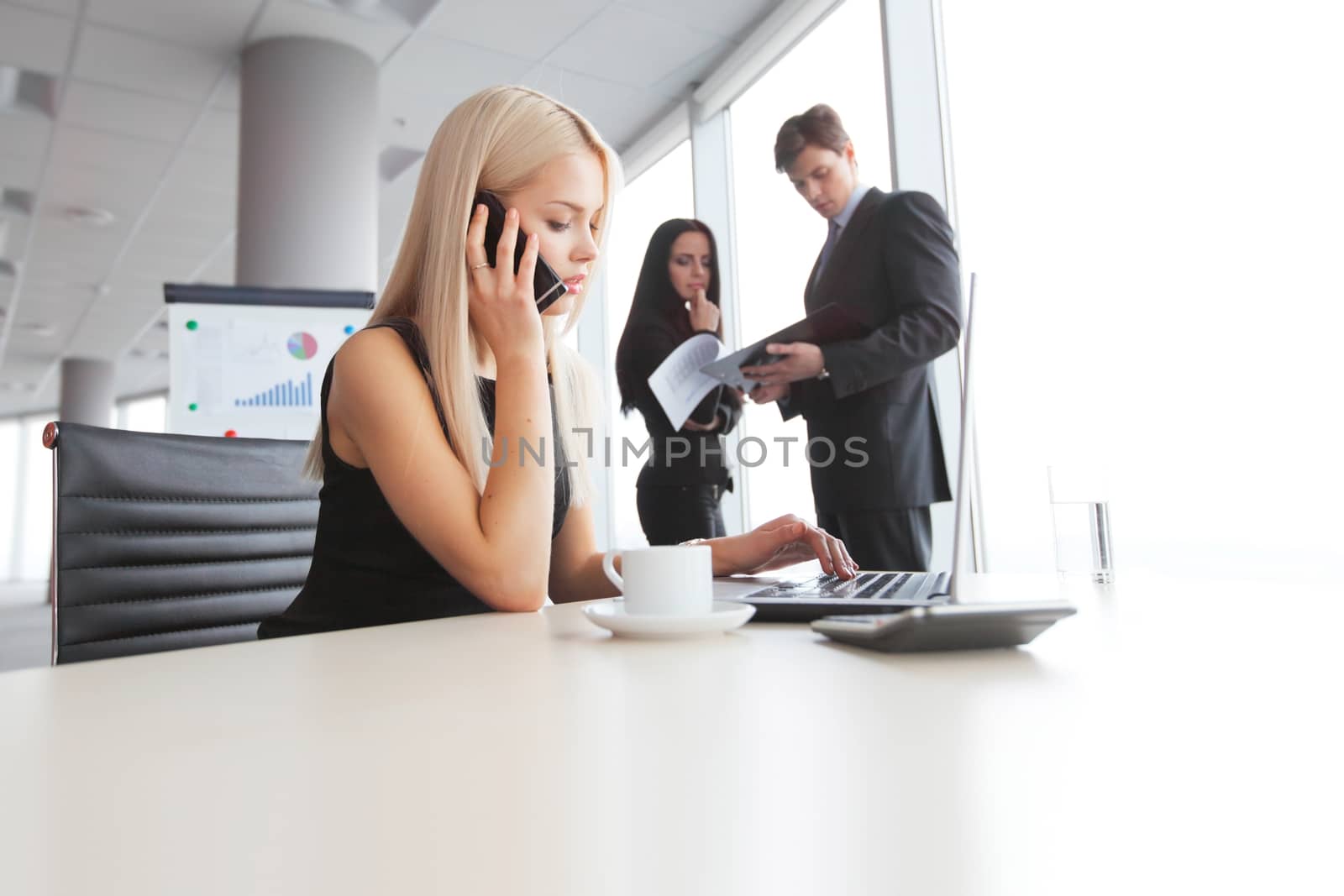 Young cute businesswoman talking on phone in office