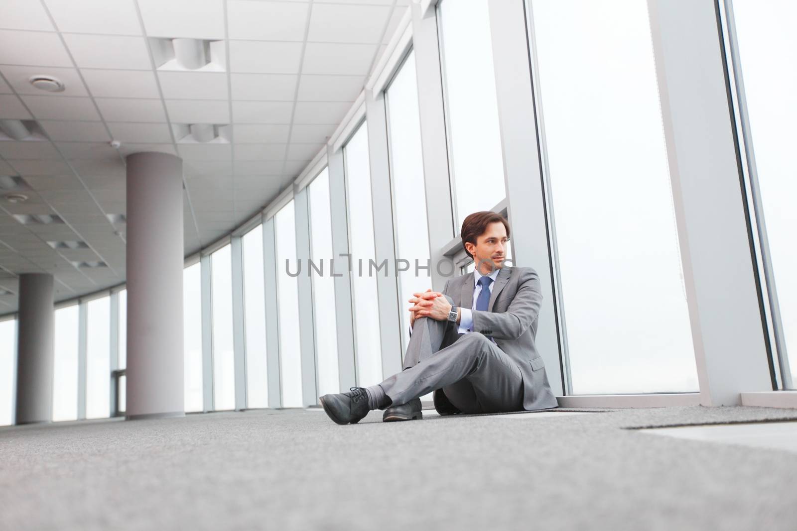 Businessman sitting on floor in office near window