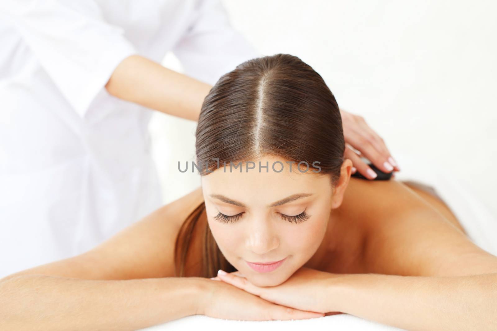 Young beautiful woman in spa getting hot stone massage