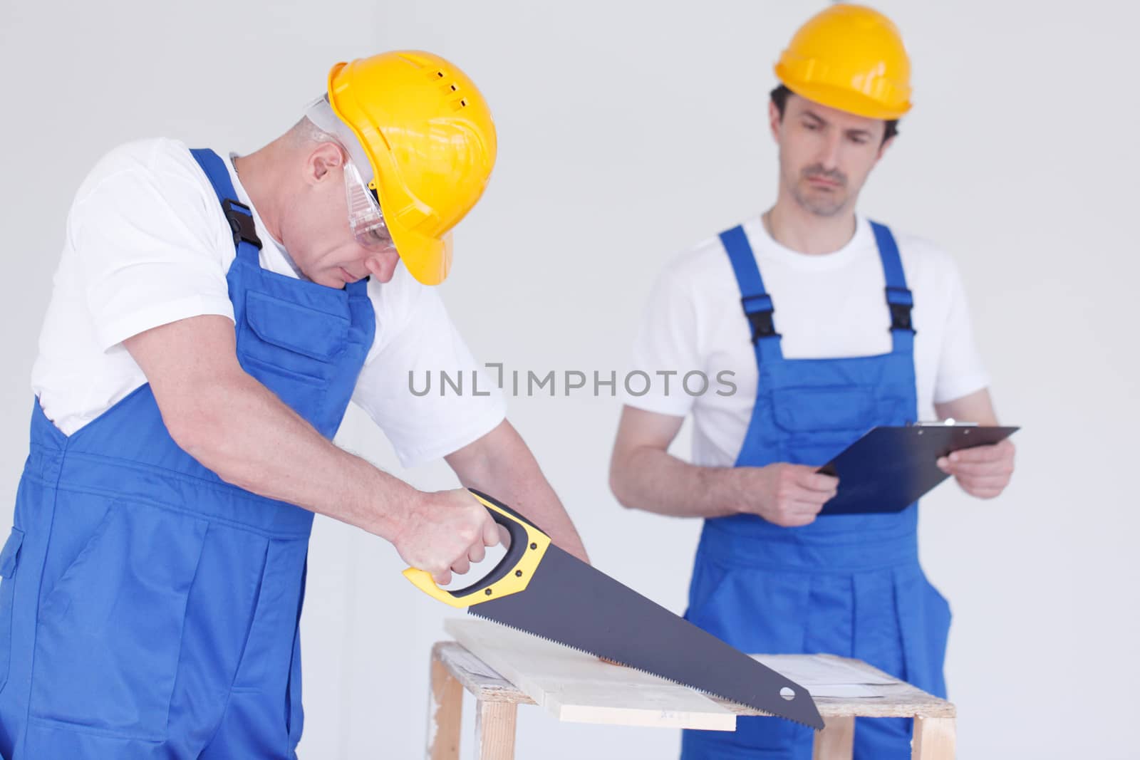 two workmen sawing wooden board