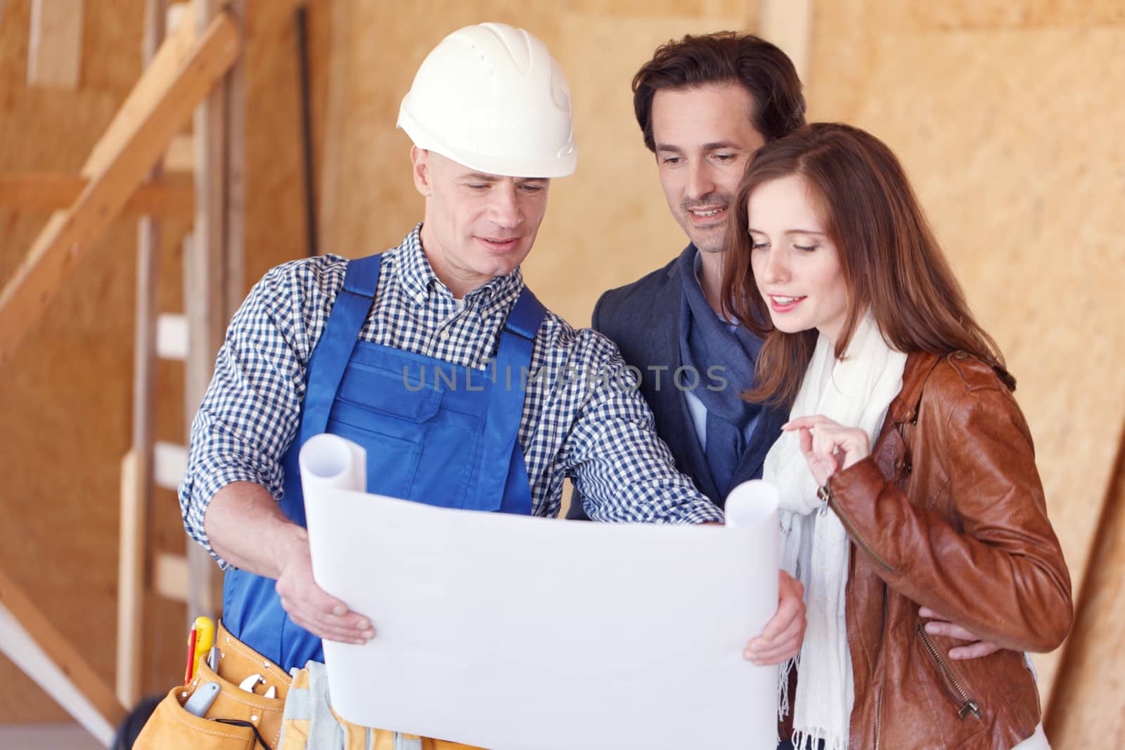 foreman shows house design plans to a young couple