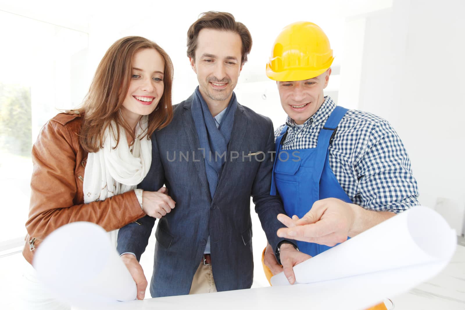 foreman shows house design plans to a young couple