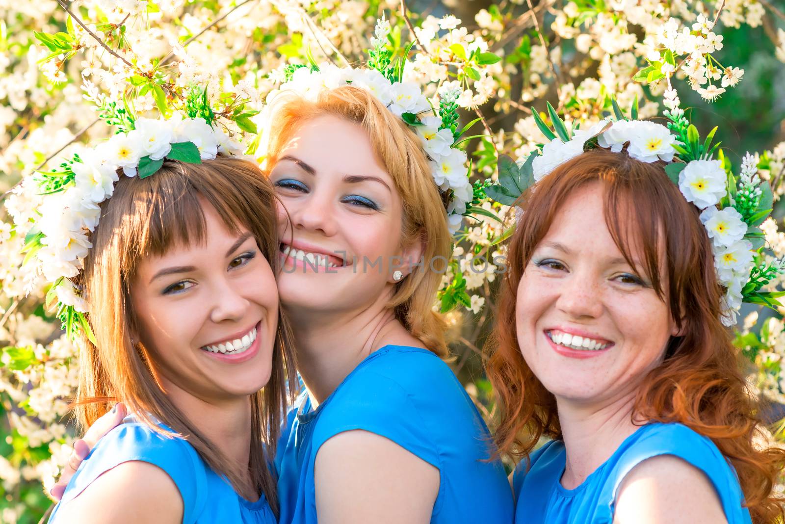 three friends with wreaths on the head near the blossoming cherry in the park