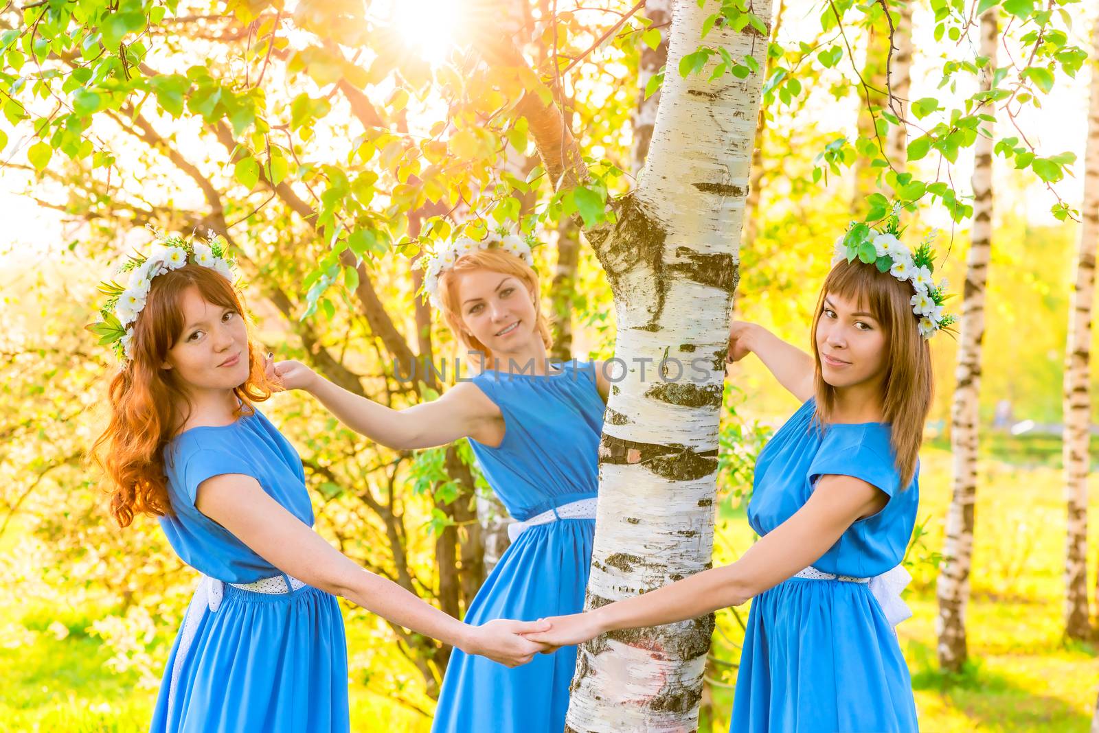 beautiful girlfriend standing around the trunk of a birch