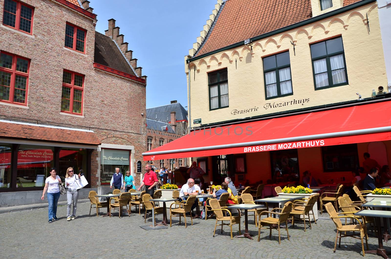 Bruges, Belgium - May 11, 2015: Tourist at outdoor cafe in Bruges, Belgium. Bruges is the capital and largest city of the province of West Flanders in the Flemish Region of Belgium. 