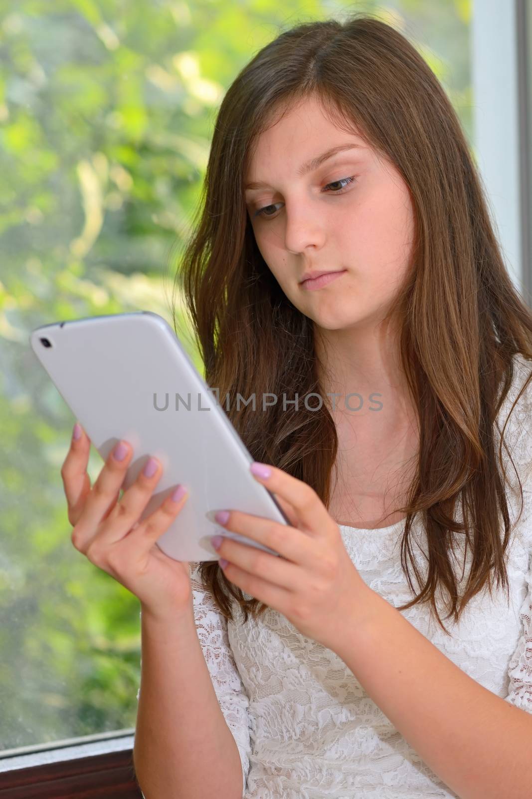 Serious attractive young girl reading information on a tablet computer