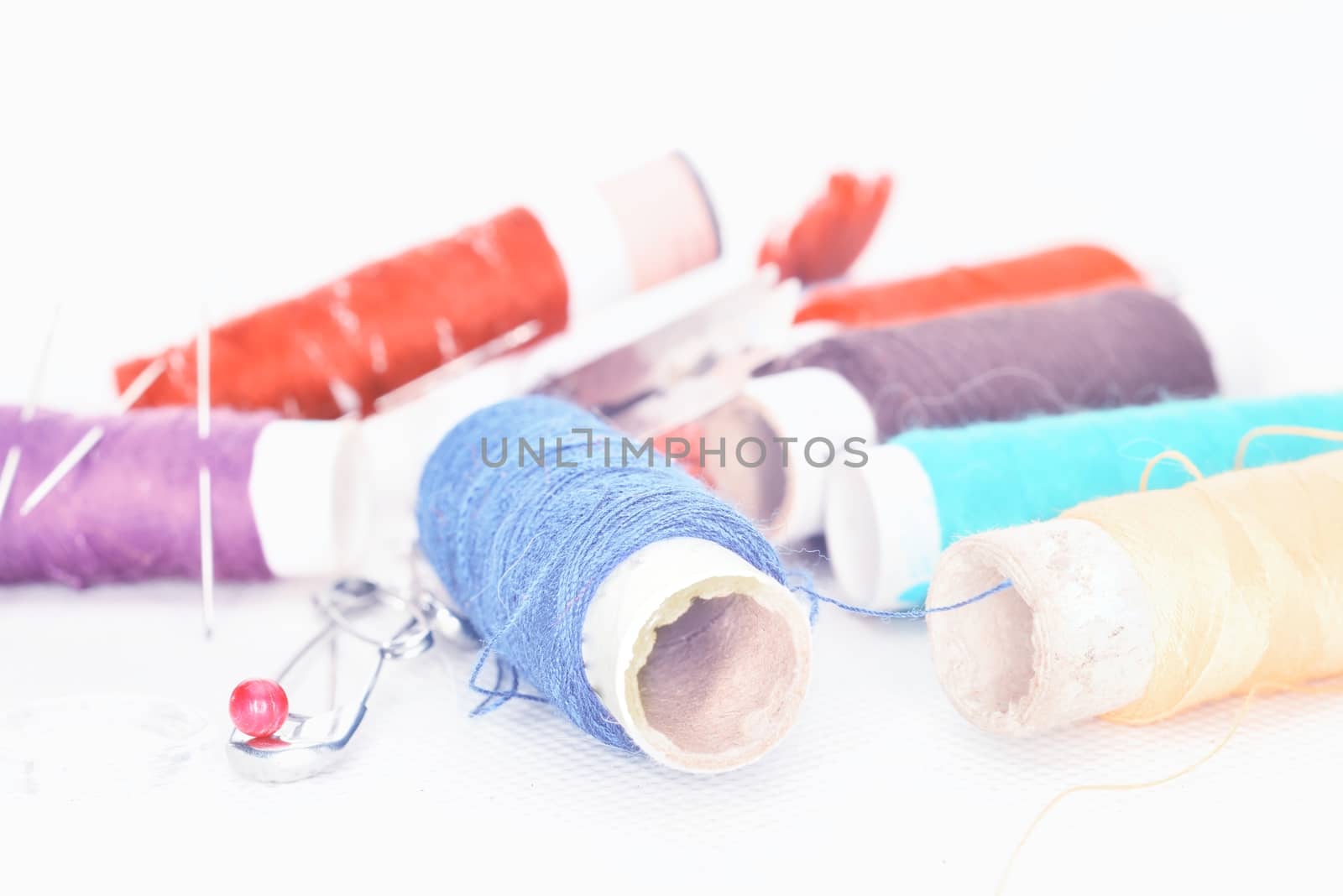 set of colored threads with needles and blade for sewing