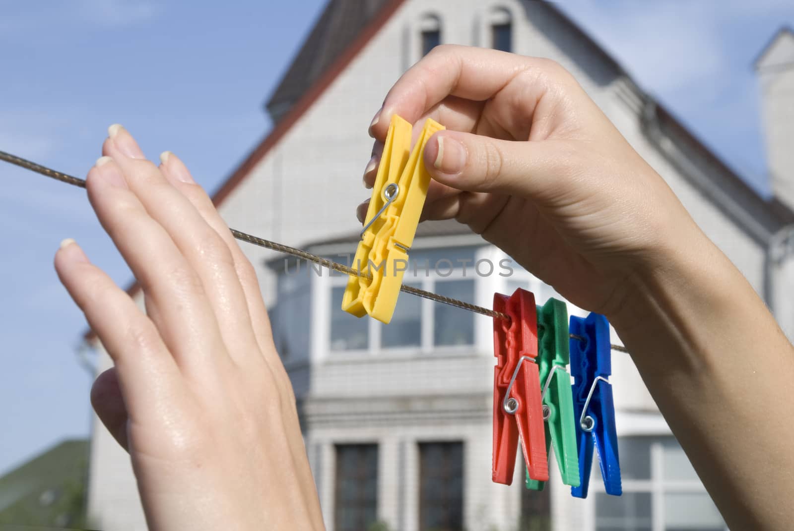 hands hang colored clothespins on a clothesline