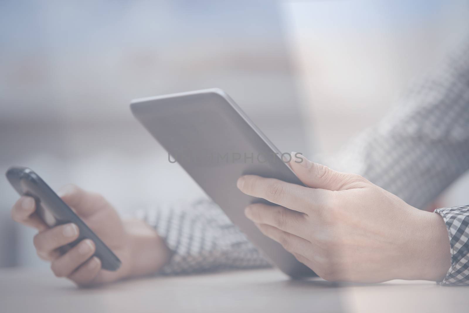 Businesswoman at office working with digital tablet and smartphone beinhd the window