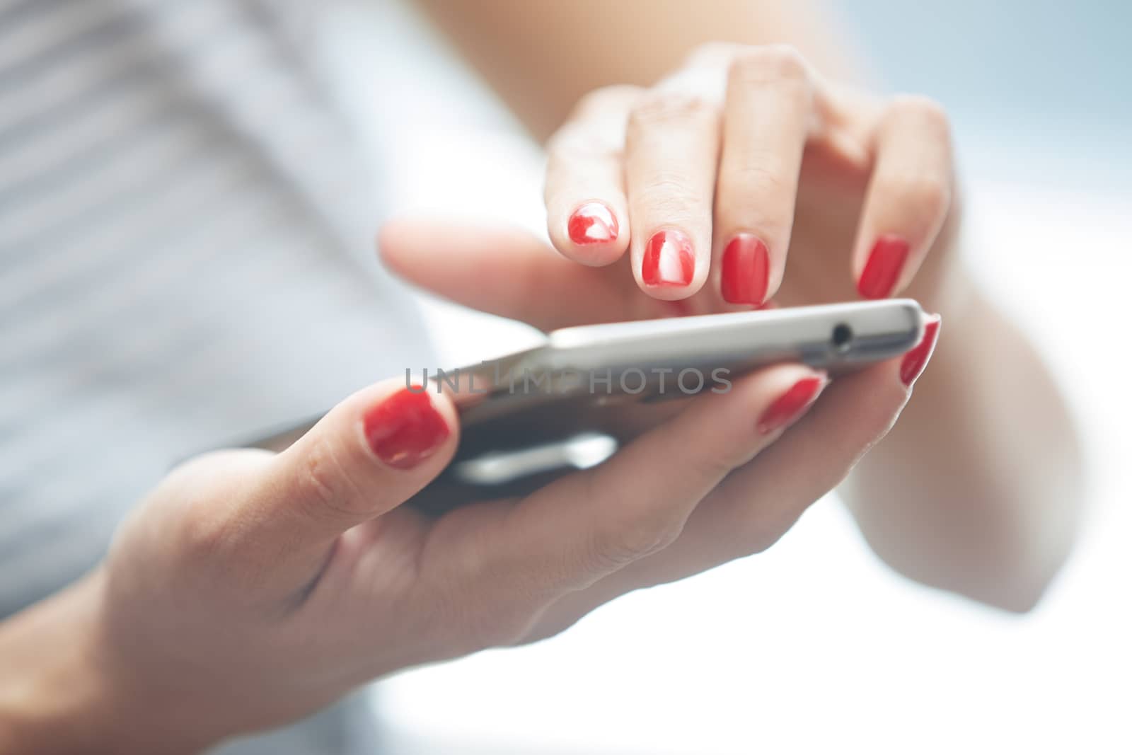 Woman with red manicure using smartphone. Horizontal photo
