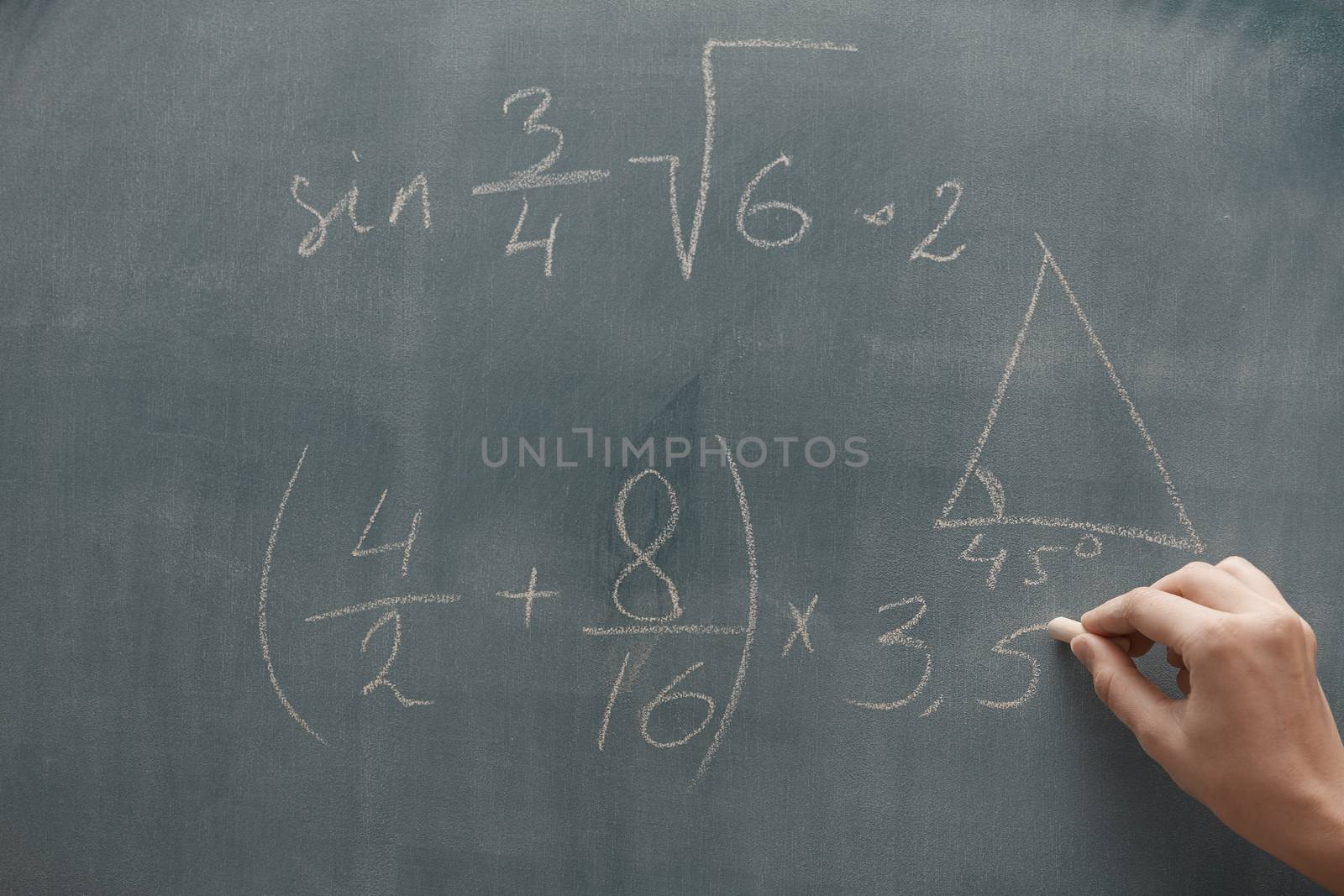 Hand of student studying mathematics and writing on a blackbroard